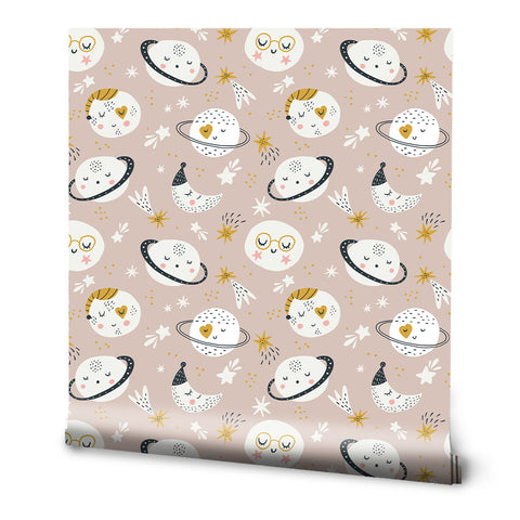 A roll of removable wallpaper with a pattern featuring moons, stars, and other space-themed elements on a pink background.
