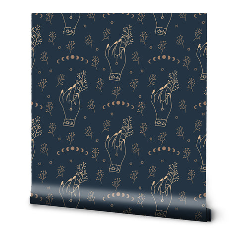 A roll of removable wallpaper with a pattern featuring hands holding plants and other whimsical dark hand art on a navy background.