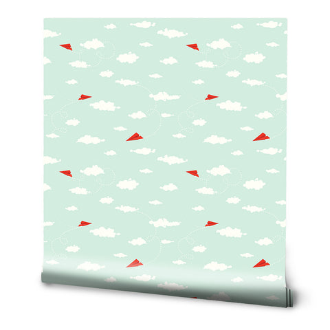A roll of removable wallpaper with a pattern of red paper planes flying against a light blue background with white clouds.