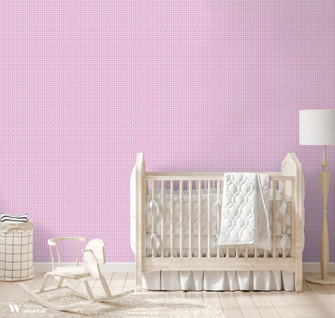 Pink wallpaper with repeating white circular motifs shown in a nursery setting with light wood furniture and neutral textiles.