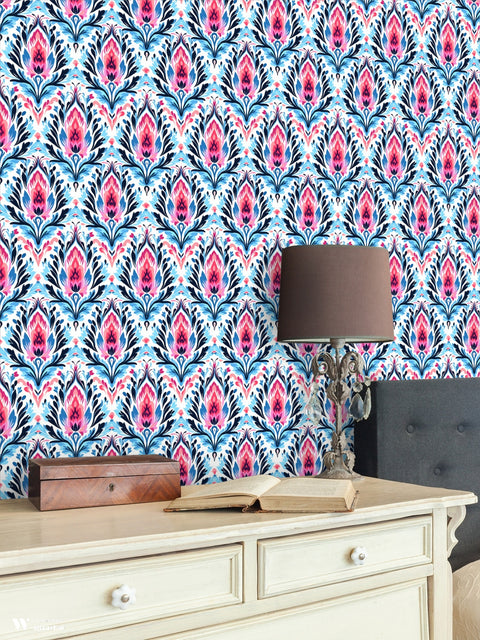 Pink and blue floral wallpaper in a bedroom setting with cream furniture and vintage lamp decor.