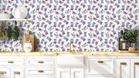 Floral wallpaper with purple, red, and cream flower bouquets shown in a bright kitchen with white cabinets and brass accents.