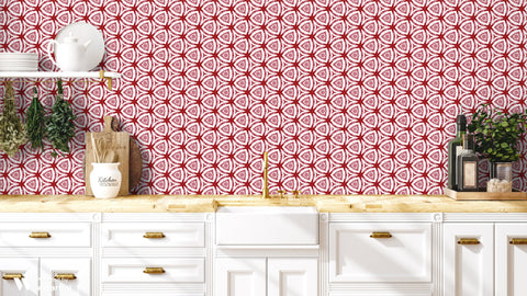 Modern kitchen with white cabinets and wooden countertop against wallpaper featuring red and white geometric floral pattern