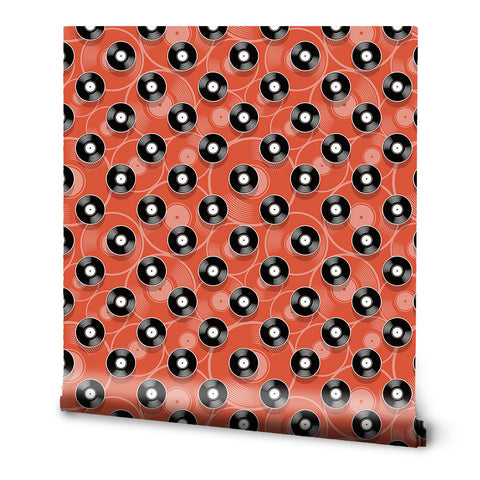 A roll of wallpaper with a retro pattern featuring black and white records on an orange background.
