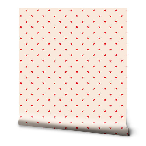 A roll of removable wallpaper with a minimalist design featuring small red hearts distributed evenly across a pink background.