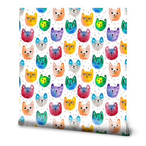 Wallpaper with a playful pattern of watercolor cat faces in bright colors like orange, green, blue, purple, and red, set against a white background with small black dash marks