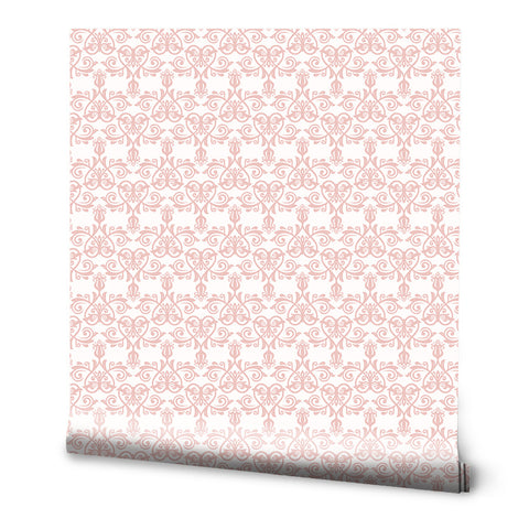 Soft pink ornamental wallpaper with a classic symmetrical design on a white background, ideal for bedrooms or living spaces.