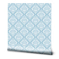 Blue wallpaper with a repeating white damask motif, creating a traditional and elegant look for bedrooms or living areas.