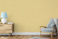 Beige wallpaper with small repeating paisley motifs in red and green, installed in a living room with a wooden cabinet, lamp, and armchair