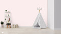 Light pink wallpaper with heart and floral motifs shown in a children’s playroom with a white teepee tent and soft toy decor.
