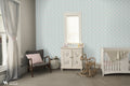 Gray wallpaper with turquoise bird and heart illustrations shown in a cozy nursery with white furniture and soft neutral decor.