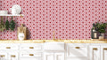 Modern kitchen with white cabinets and wooden countertop against wallpaper featuring red and white geometric floral pattern