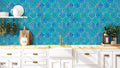 Kitchen wall with blue Moroccan-style quatrefoil wallpaper featuring gold outlines, paired with white cabinets, wooden countertop, and hanging herbs