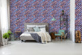 Bedroom with gray bed and modern decor against wallpaper featuring geometric lattice pattern in blue, bronze, and purple on dark navy background