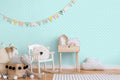 Light turquoise damask wallpaper shown in a children’s room with wooden furniture and playful decor.