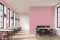 Cafe interior with wooden tables and black seating against wallpaper featuring red and white geometric floral pattern