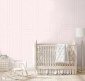 Light pink wallpaper with delicate heart and floral motifs displayed in a nursery with a wooden crib, rocking horse, and neutral decor.