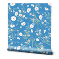 A roll of floral wallpaper with a blue background and white daisy patterns.